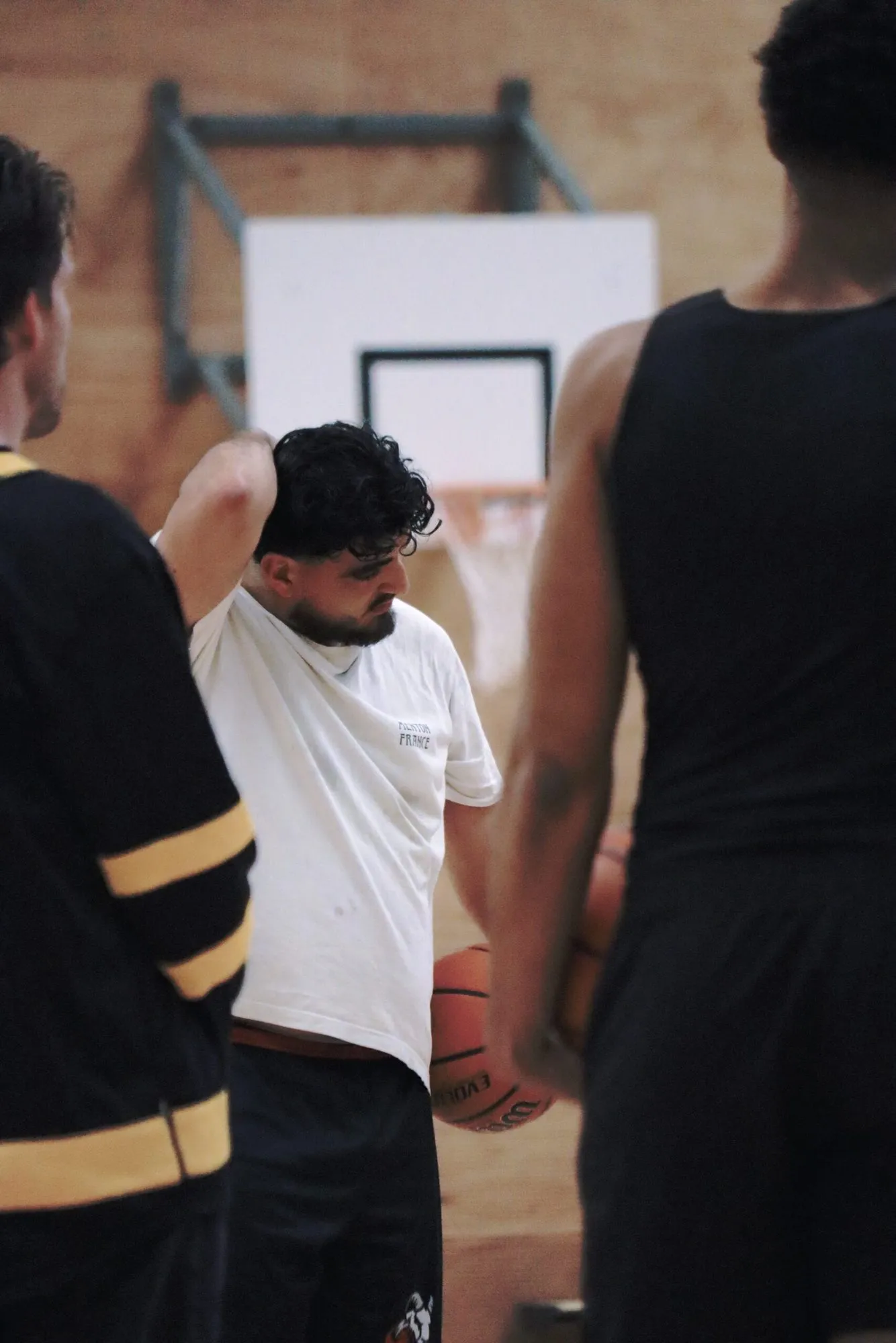 Coach met een bal onder de arm in gesprek met spelers