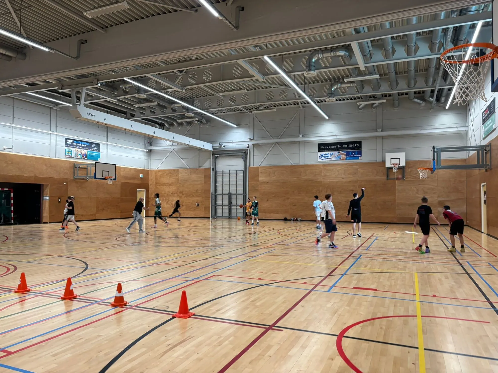 Wijd overzicht van de zaal in de Erasmushal met pylonen op de vloer tijdens een training