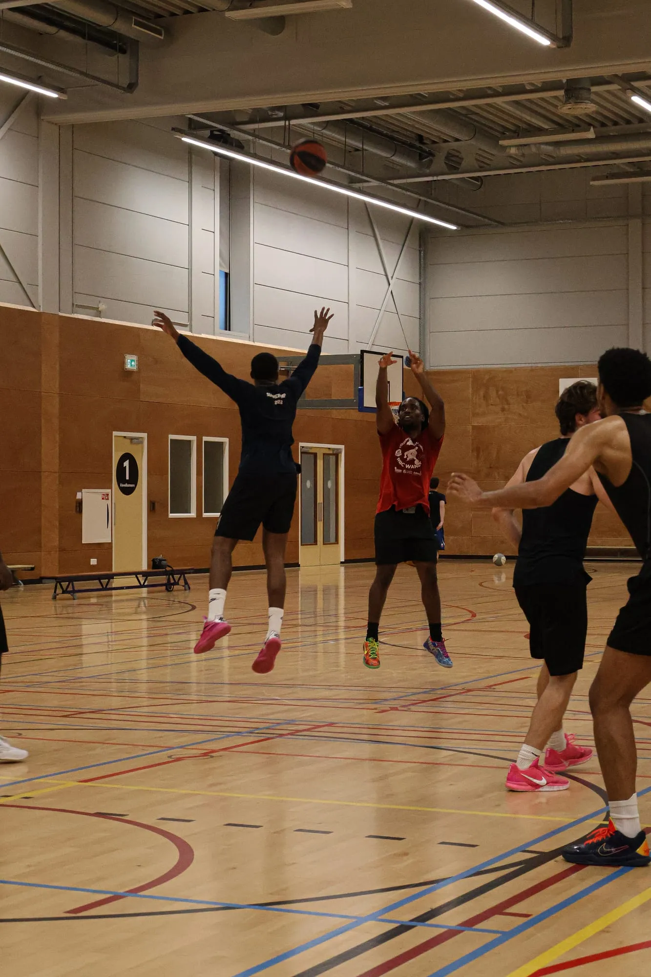 Spelers in een partijtje in de zaal, met een schot op de basket