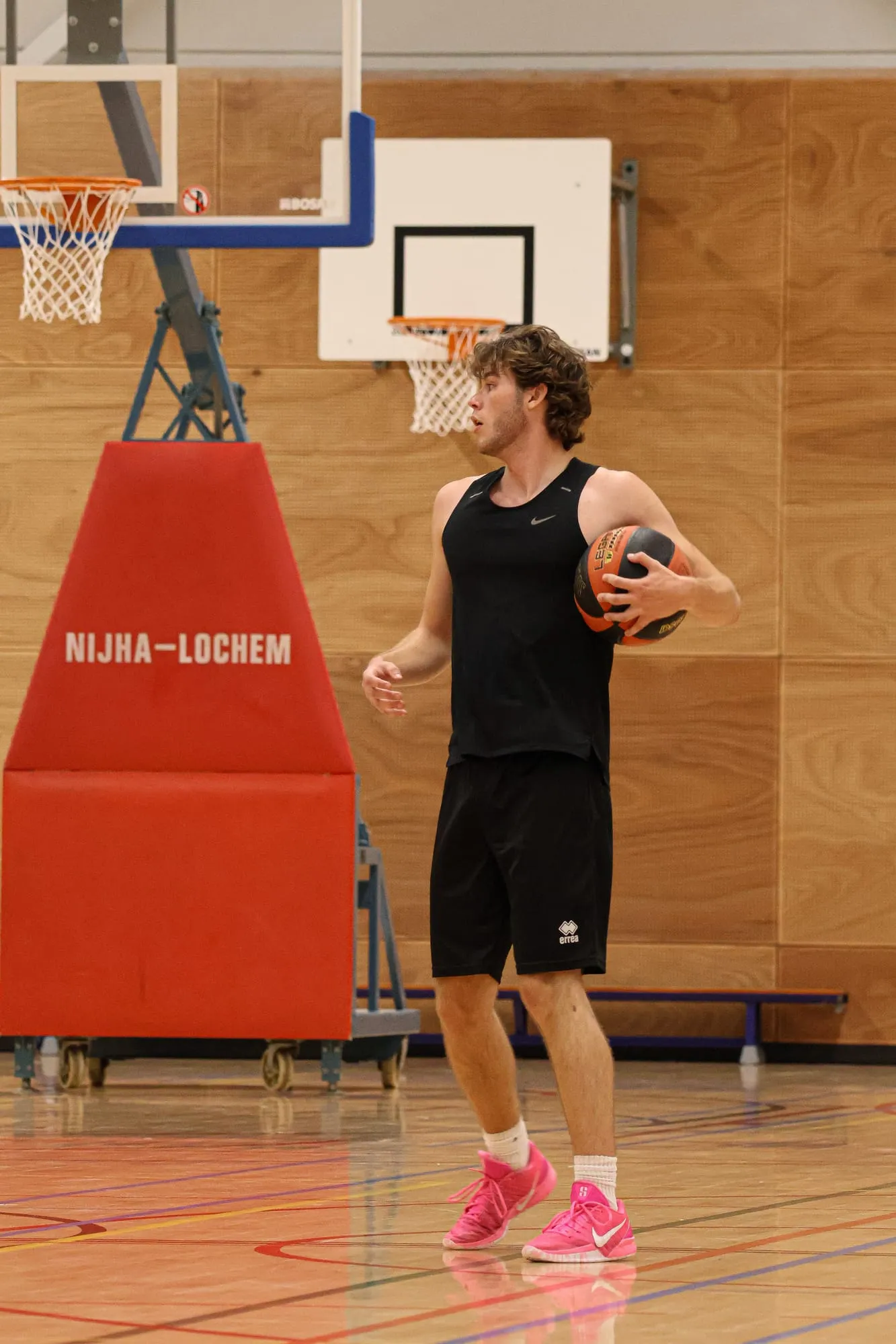 Speler met een bal in zijn handen naast de beschermrand van de basket