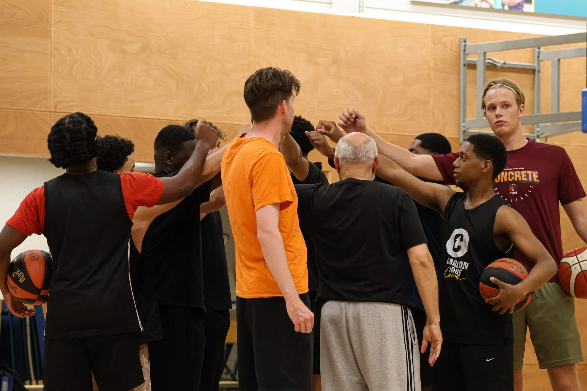 Spelers leggen hun handen bij elkaar in een kring voor de training