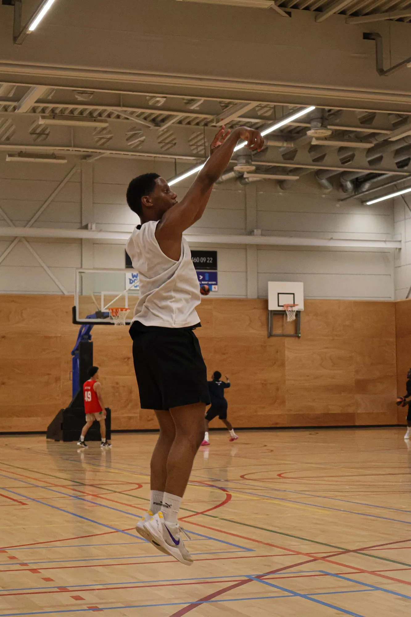 Speler in een wit shirt neemt een jump shot vanaf de vrijeworplijn
