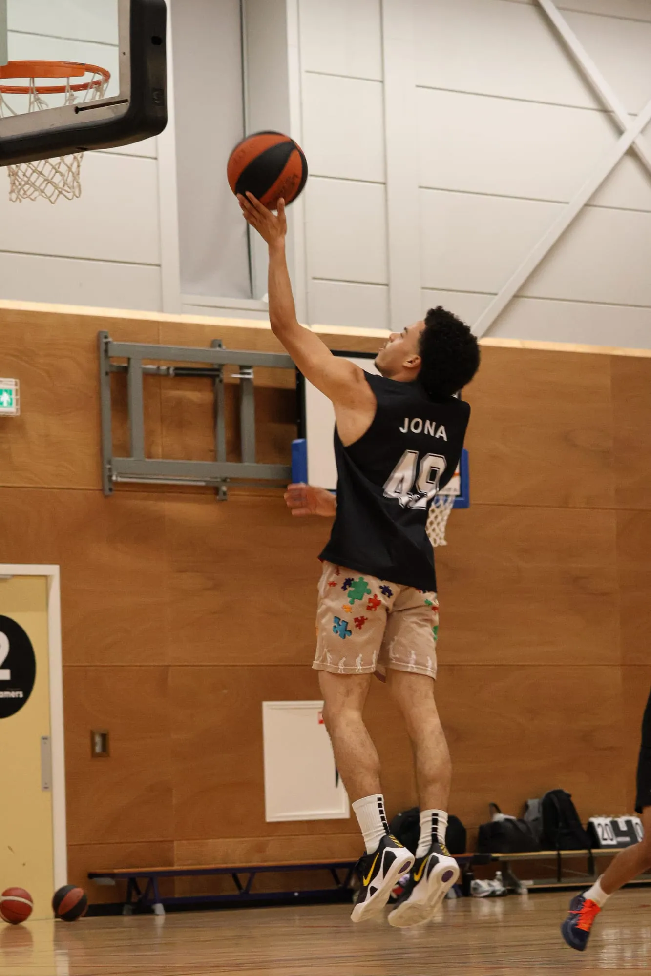 Speler legt de bal met gestrekte arm in de basket