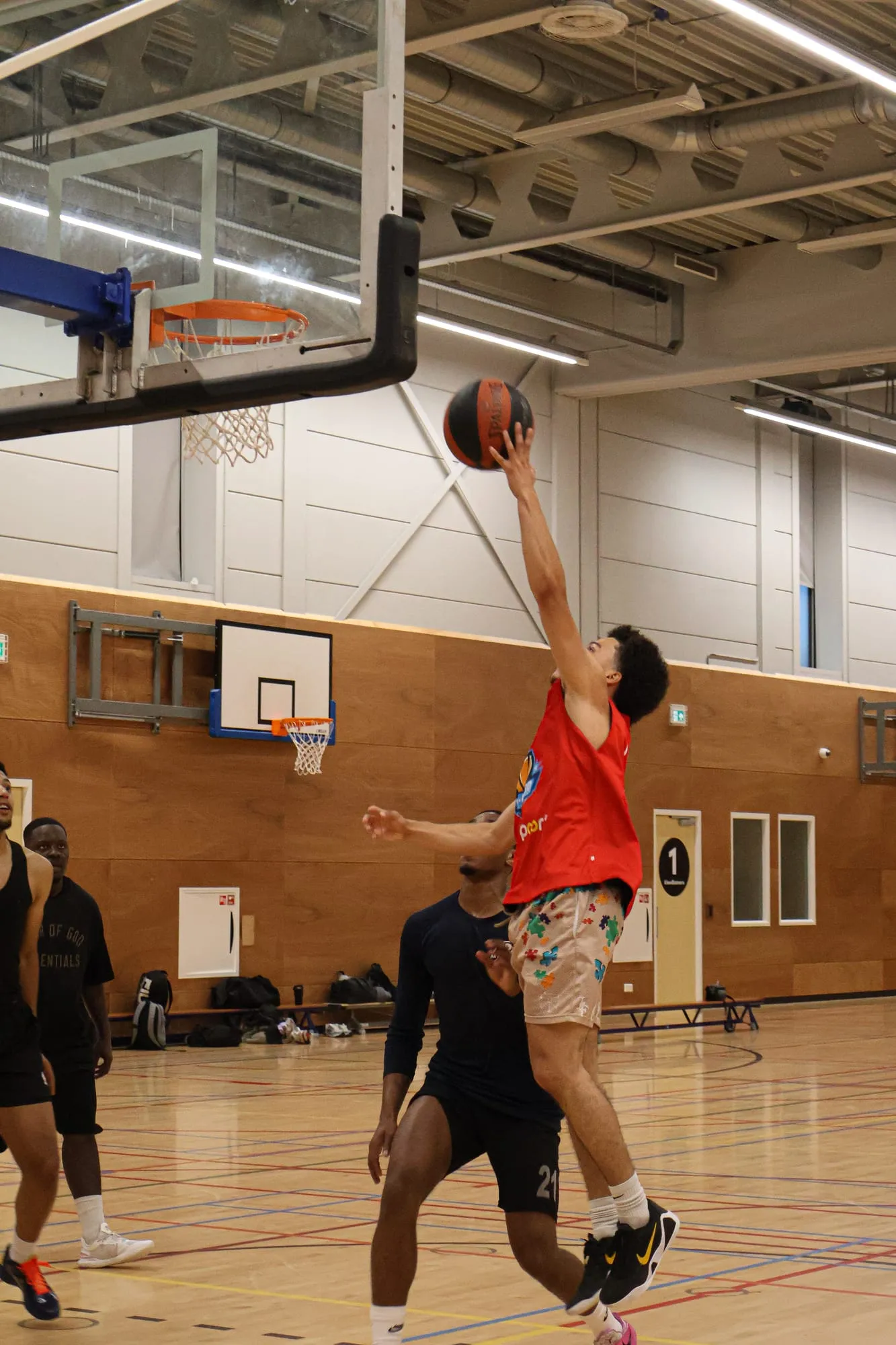 Speler in een rood shirt maakt een layup onder de basket