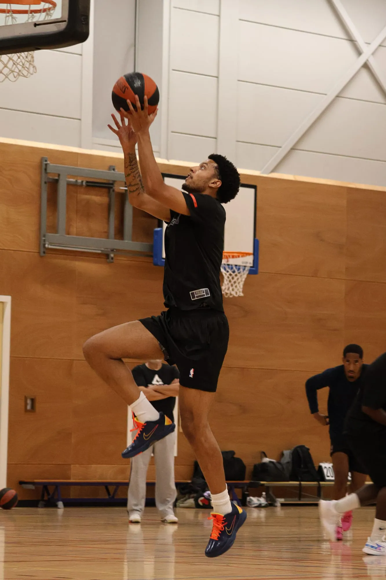 Speler springt op naar de basket tijdens een training in de Erasmushal