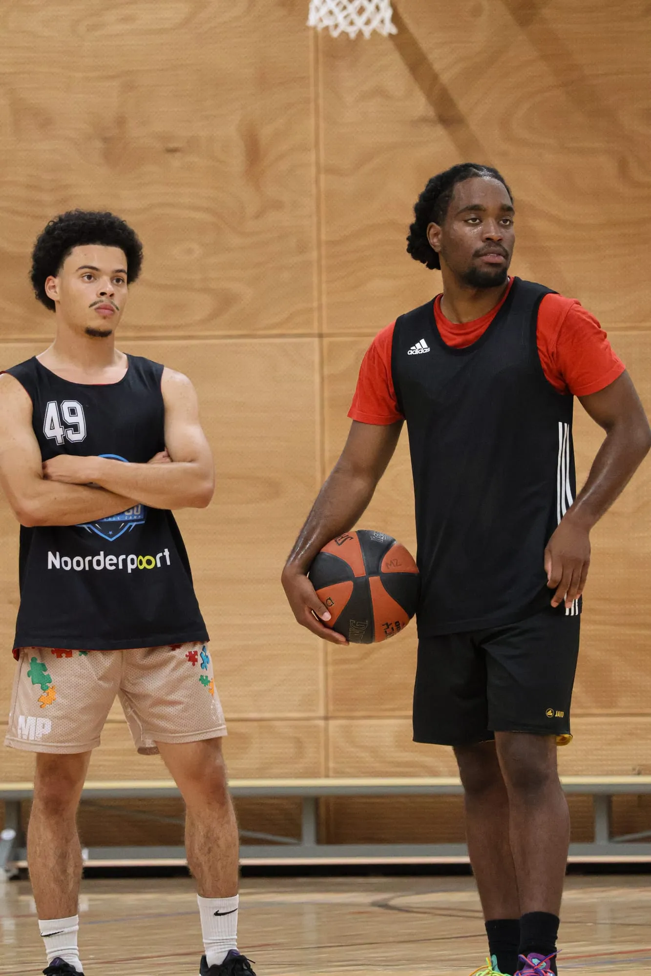 Twee spelers wachten met een bal op hun beurt bij een oefening